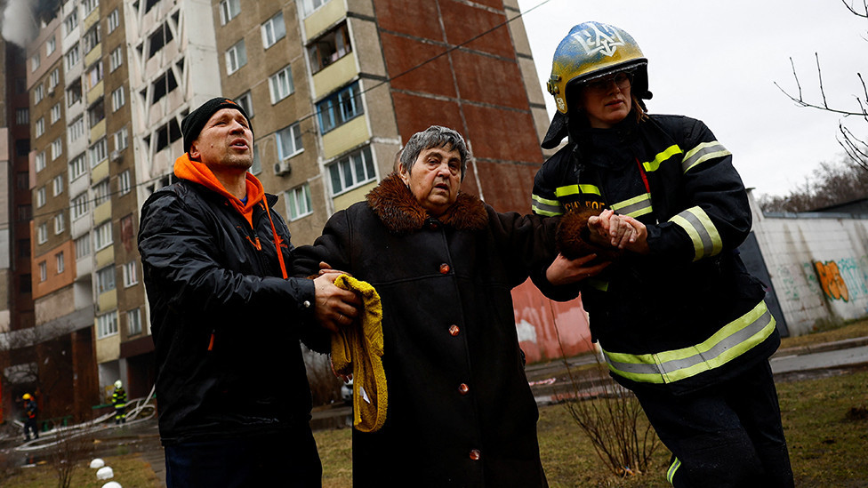 Firefighters help a woman from a building damaged during a Russian missile strike, amid Russia's attack on Ukraine, in Kyiv, Ukraine February 7, 2024