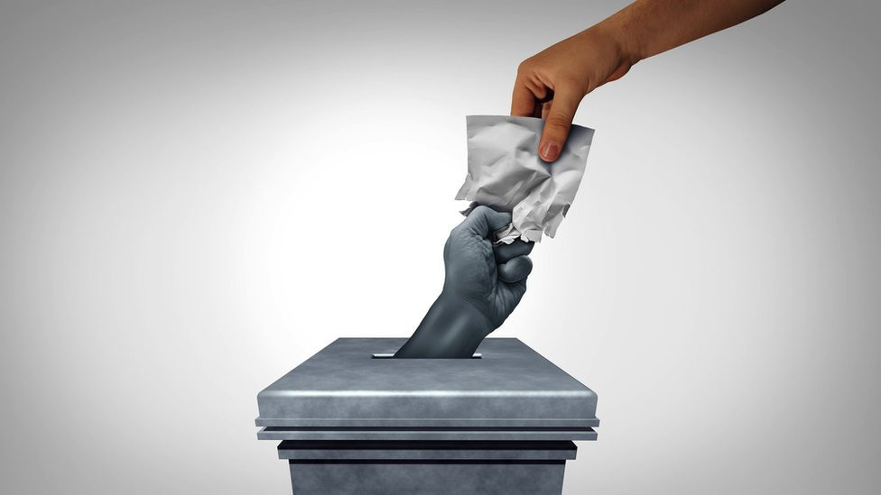 Voting suppression destruction of votes and electoral fraud or election crime or vote tampering and rigging as a hand crushing a ballot paper as an illegal electoral scheme with 3D illustration elements