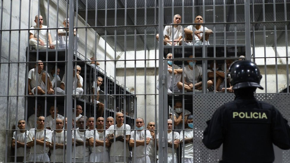 Prisoners in a cell sitting on bunk beds four-storeys high