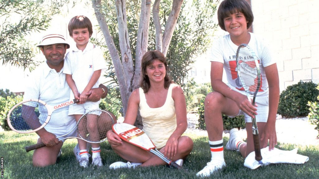 The Agassi family, with a young Andre, pose in front of a tree while holding tennis racquets