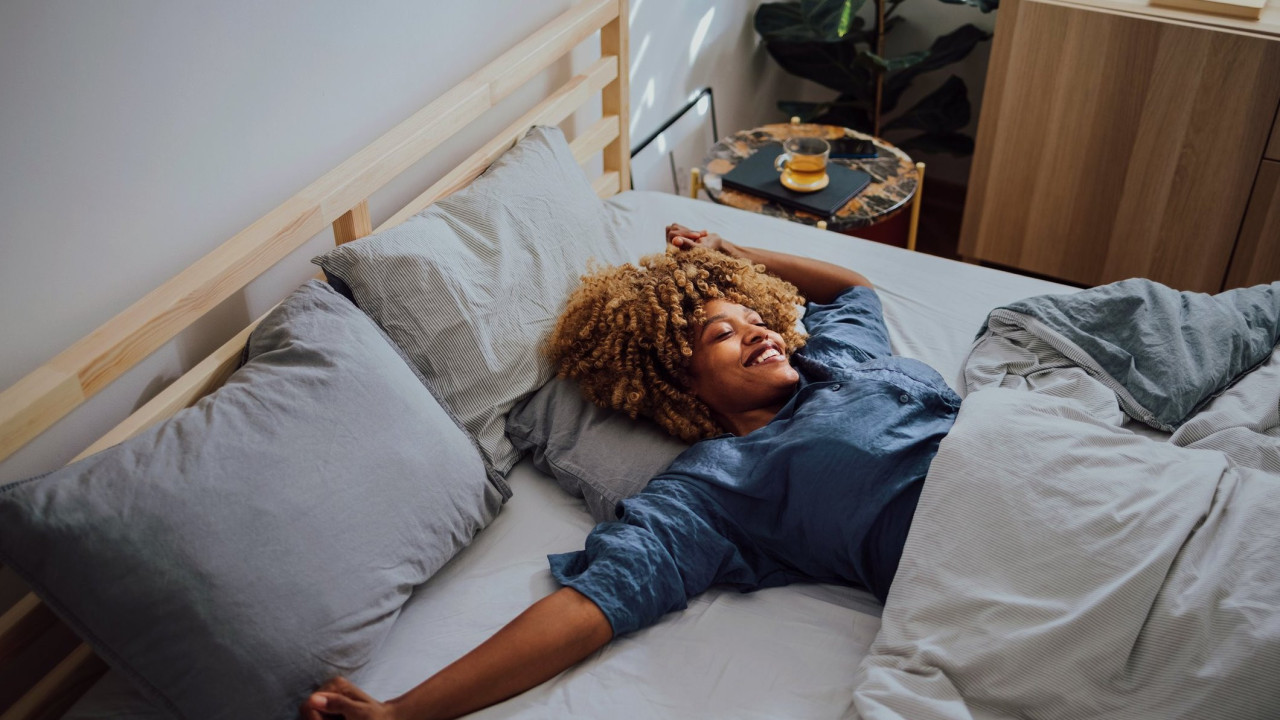 A woman smiles as she sleeps alone in a bed