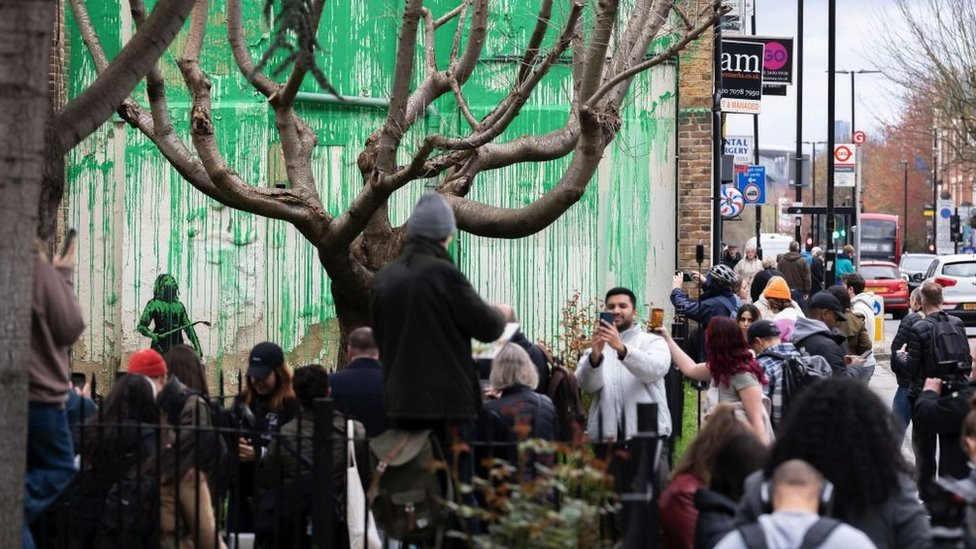 People crowd around the mural taking photos