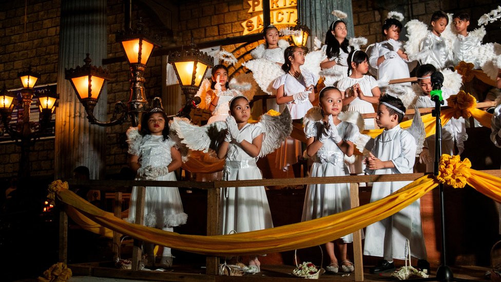 Children dressed as angels pray ahead of the procession