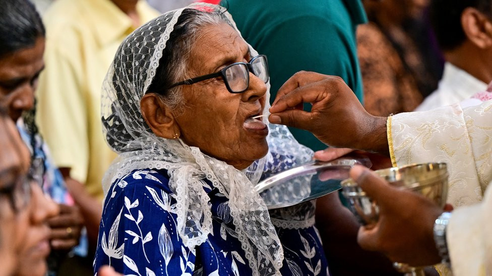 A Catholic priest gives the Holy communion to a Christian devotee during an Easter Sunday service commemorating the resurrection of Jesus as part of the Holy Week celebrations and to mark the fifth anniversary of the Easter Sunday attack, at St. Sebastian's Church in Katuwapitiya.