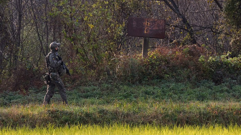 Soldier walk near the sign that marks the border