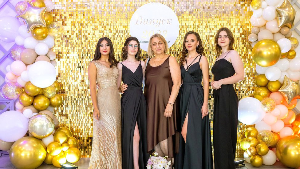 (From left to right) Sofiia, Aliesia, their former teacher Svetlana, Iryna and Yuliia in Mykolaiv, celebrating their prom in July 2023