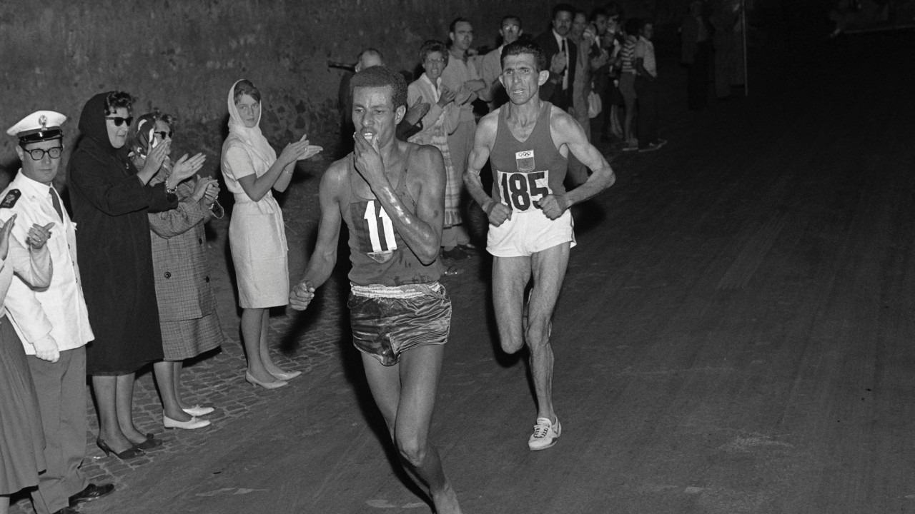 Ethiopian athlete Abebe Bikila runs barefoot ahead of another competitor