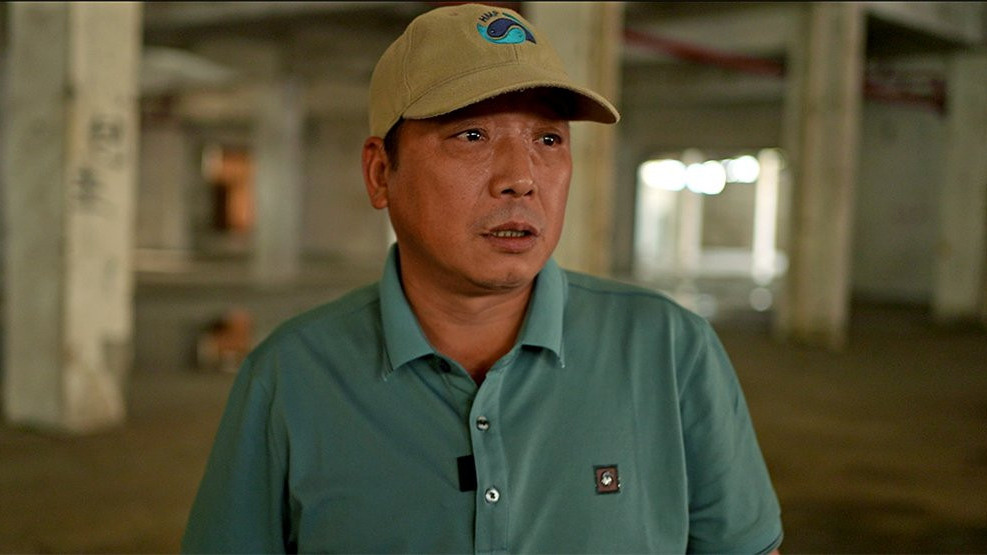 Ren Wenbing stands inside empty factory