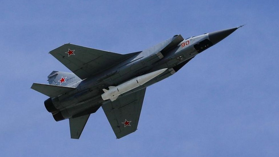 Fighter jet with Kinzhal hypersonic missile on its underside, pictured against blue sky