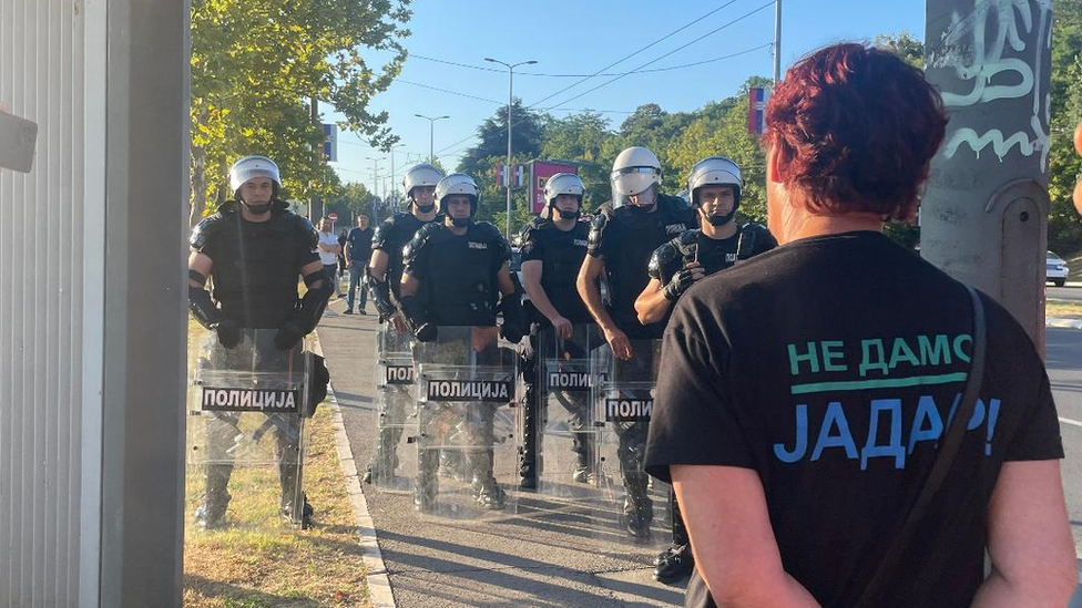 Policija u opremi za razbijanje demonstracija i demonstrantkinja se gledaju