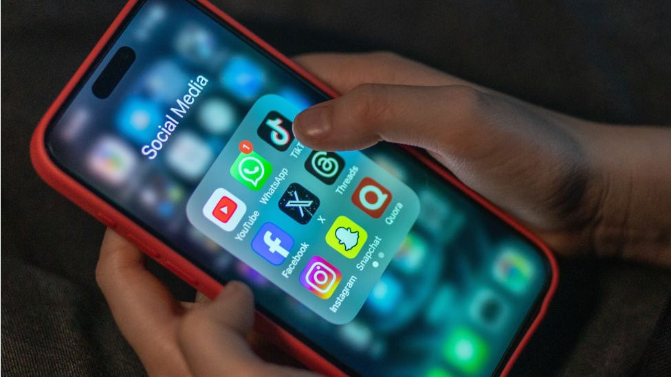 An iPhone screen showing social media apps including TikTok, Instagram, Facebook and X