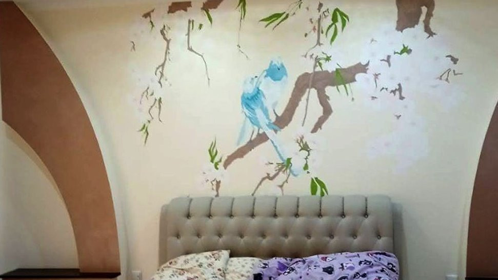 Bedroom with cherry blossom and doves painted on the wall by the bed.