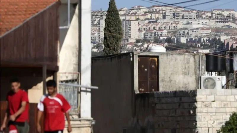 Dvojica mladića iza kojih se naziru zgrade na Zapadnim obalama
