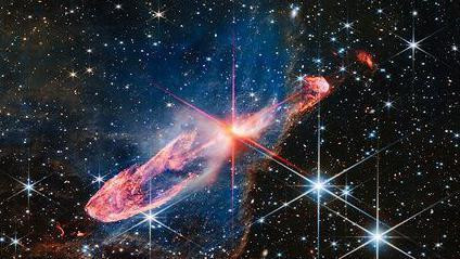 Mala jarko crvena zvezda osvetljava gusti vrtložni prsten gasa oko sebe, a u pozadini je polje zvezda