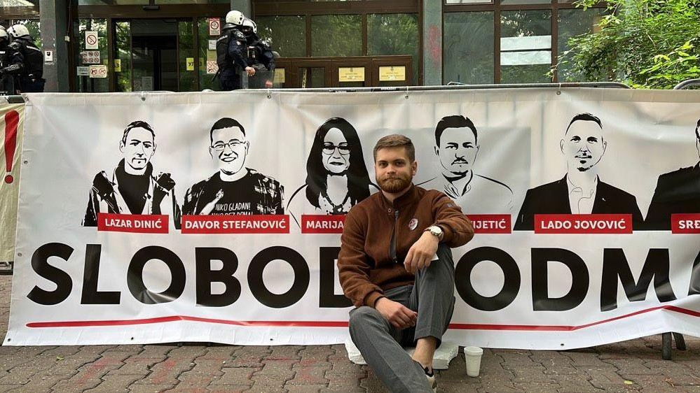 Sin Marije Vasić, Milan Čanak, ispred transparenta sa likovima pritvorenih