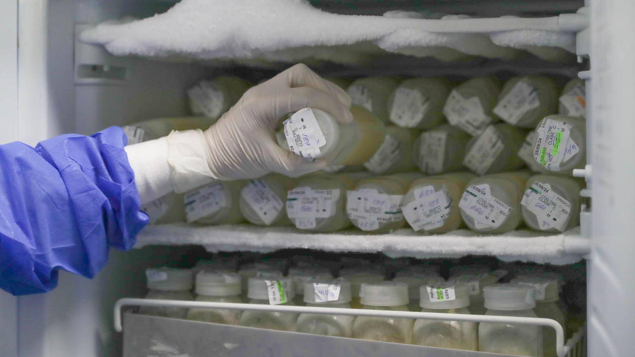 osoba sa rukavicama vadi flašu mleka iz frižidera 