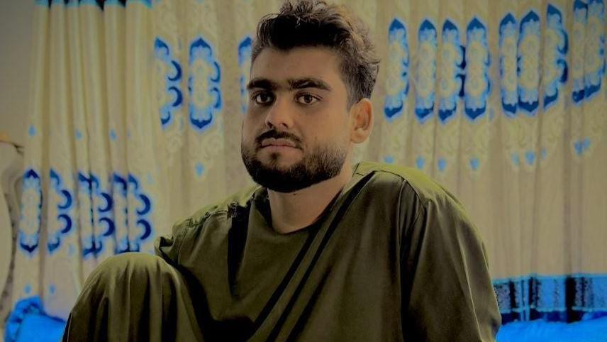  Qudratullah  sitting on a blue bedsheet 