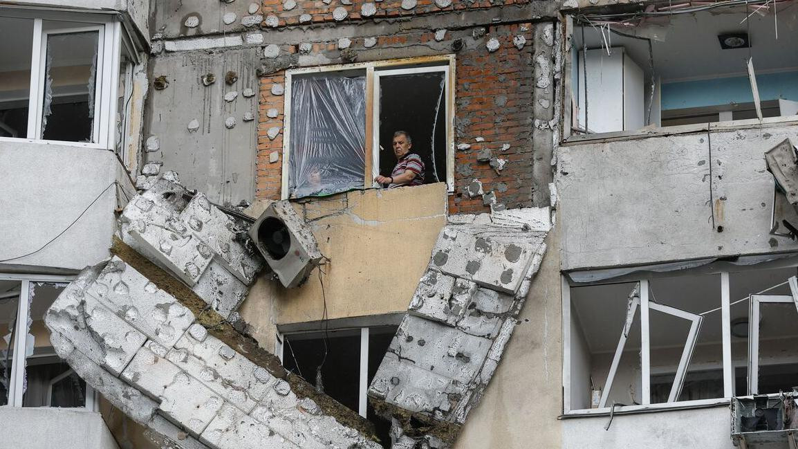 Čovek na prozoru razrušene zgrade 