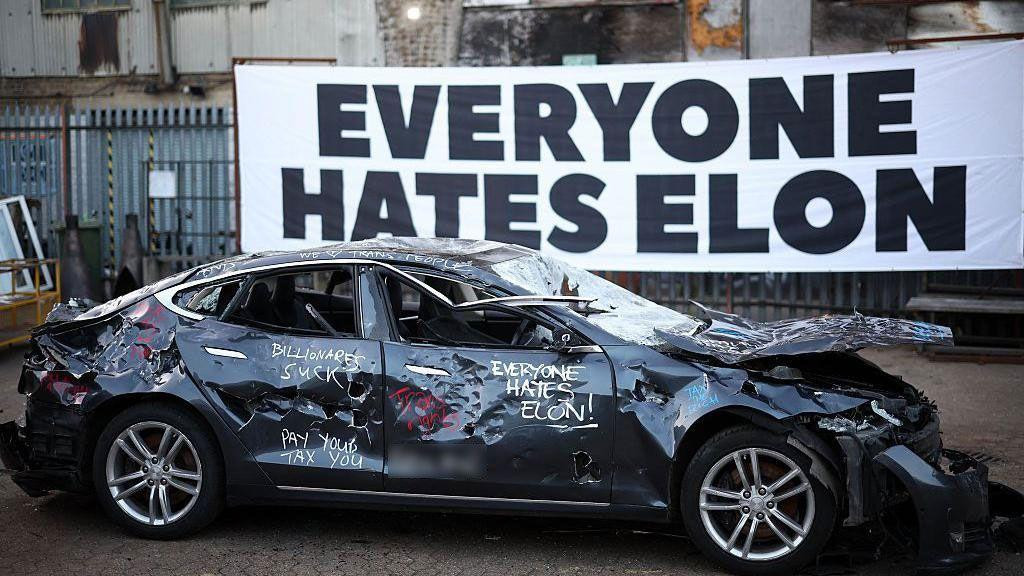 Uništen crni automobil iznad njega protesna poruka