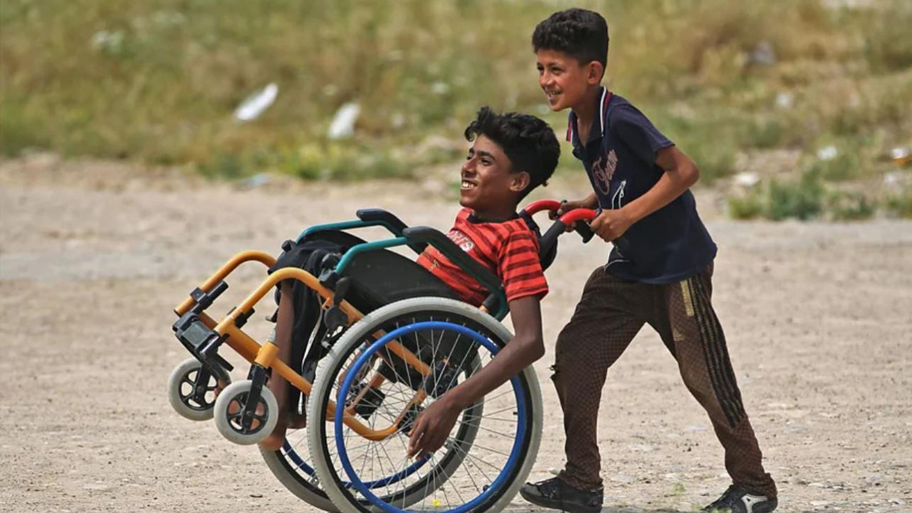Dečak pomaže prijatelju da se kreće u invalidskim kolicima