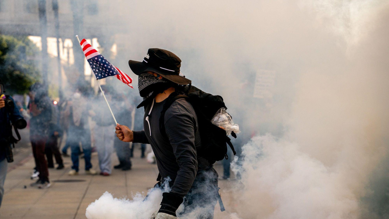 Muškarac u dimu suzavca drži američku zastavu