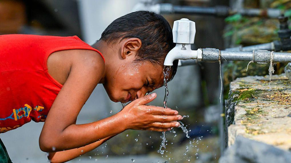 Dečak pije vodu sa česme