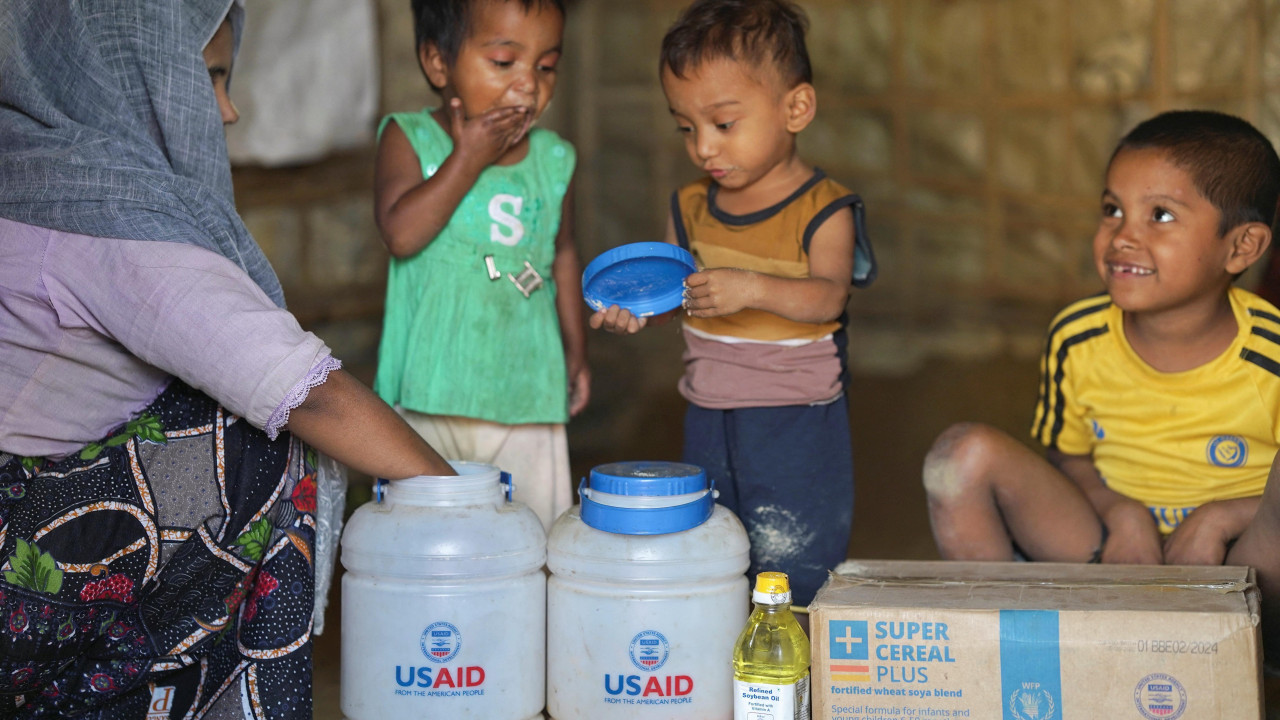 Rohingya children eat from jars with the USAID logo on them, at a refugee camp in Cox's Bazar, Bangladesh