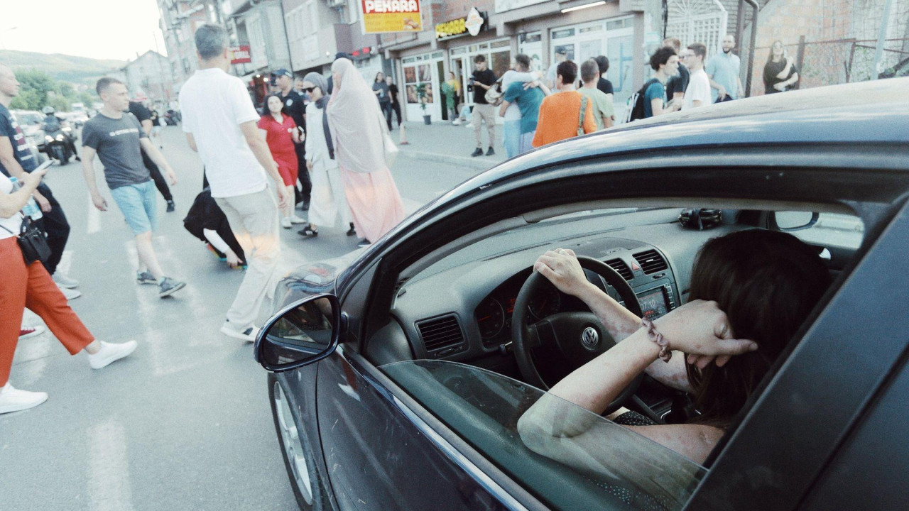 Muškarac u automobilu čeka da pređe ulicu