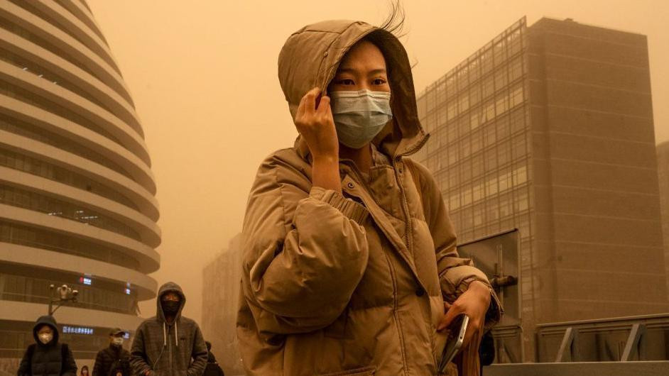 kineskinja sa maskom preko lica zbog peščane oluje