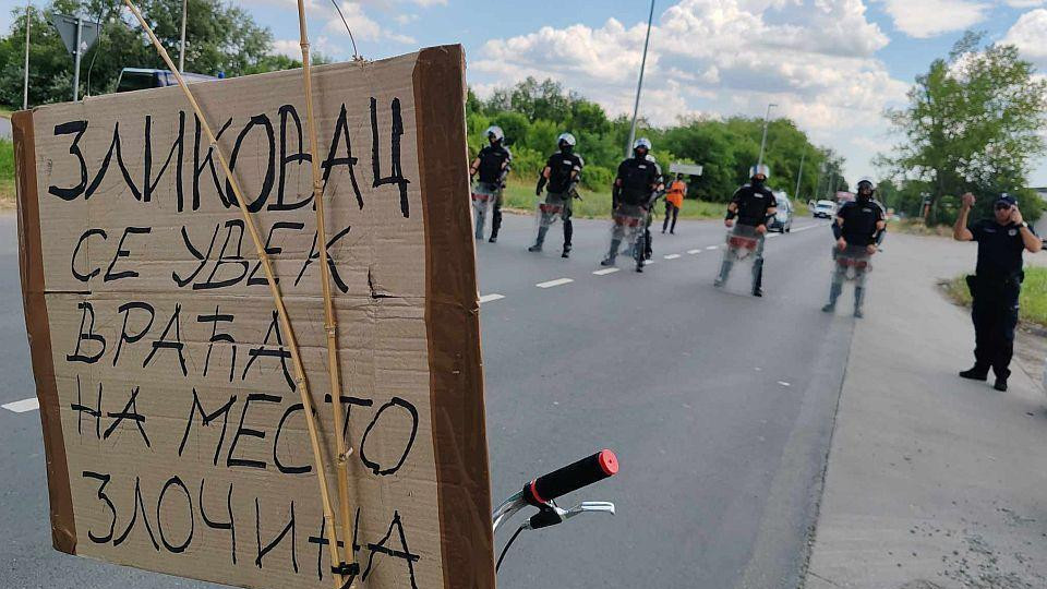 policija u Novom Sadu. Ispred njih bicikla sa transparentom "Zločinac se uvek vraća na mesto zločina"