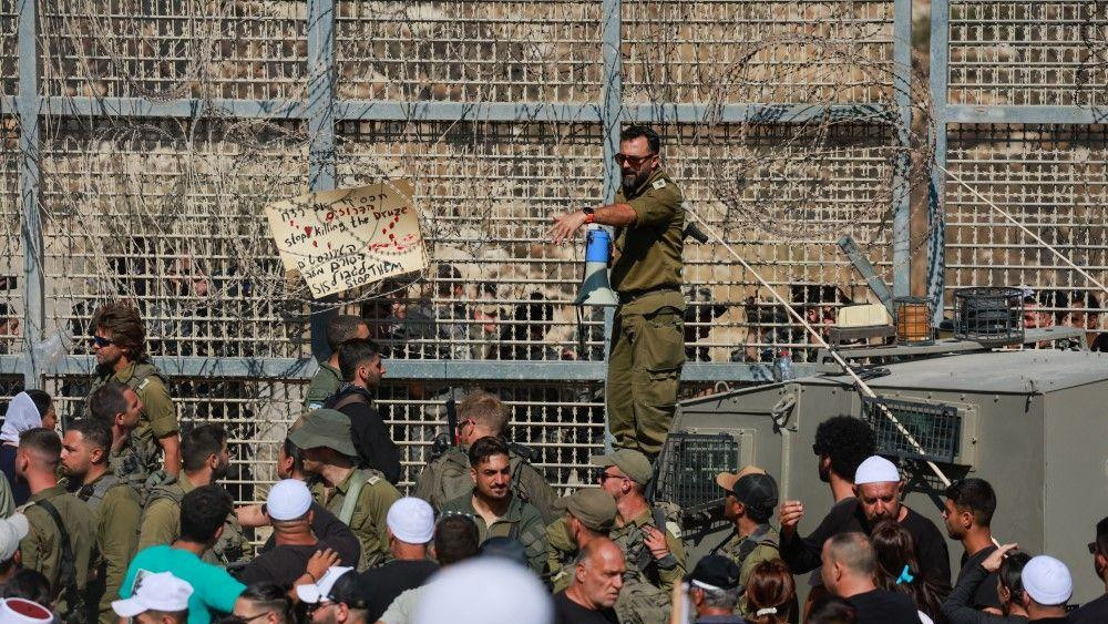 Izraelski vojnik drži megafon dok se izraelski Druzi okupljaju, blizu linije prekida vatre između Golanske visoravni koju je Izrael okupirao i Sirije