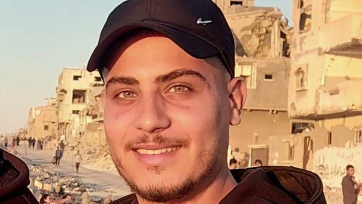 Mladić u kačketu, nasmejan, gleda u kameru