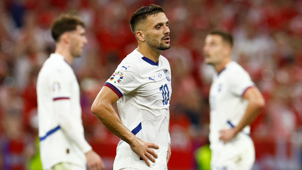 Dušan Tadić u belom dresu Srbije na utakmici sa rukama na struku, iza njega dva igrača