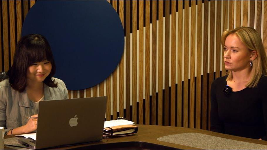 Žena se osmehuje u laptop - razgovara sa nekim preko video poziva. Druga žena je gleda.