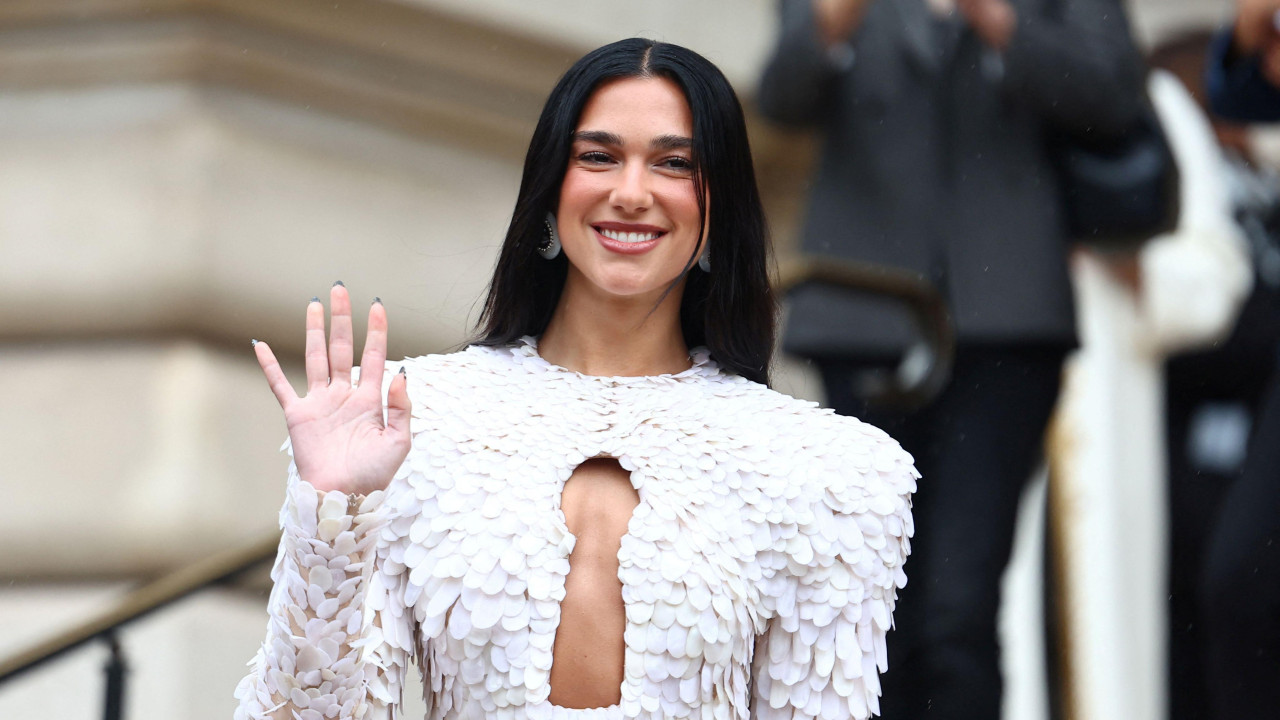 Dua Lipa u beloj haljini sa isečenim delom na dekolteu, puštenom crnom kosom maše publici