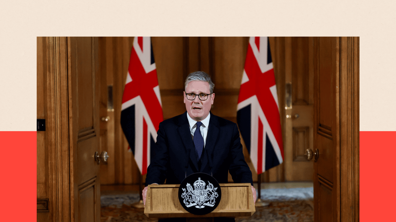 Kir Starmer drži govor u Dauning ulici 10, stoji ispred dve britanske zastave sa strana, ima crno odelo, belu košulju i plavu kravatu, nosi naočale