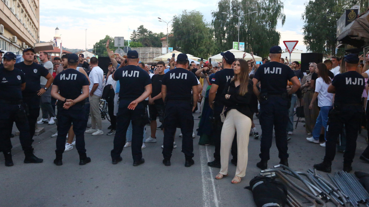 Devojka u tamnoj majici i belim pantalonama ispred kordona policije koji joj je okrenut leđima