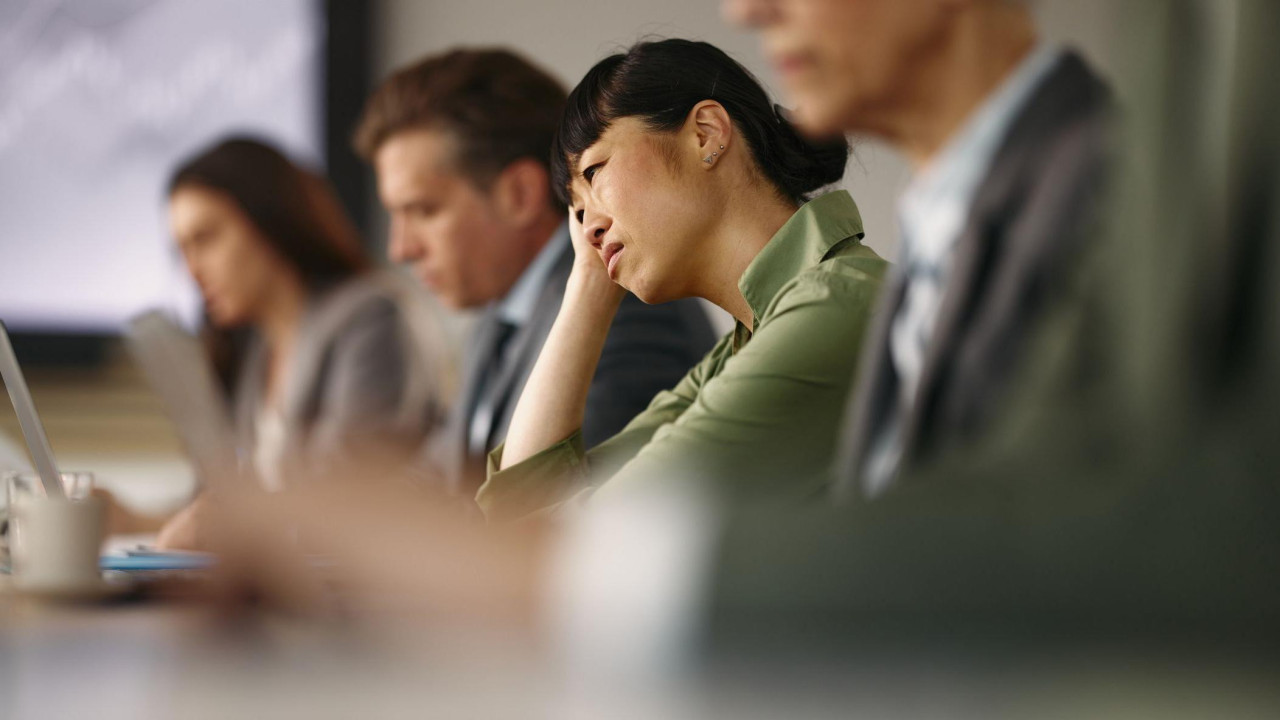 Iscrpljena žena među kolegama na sastanku