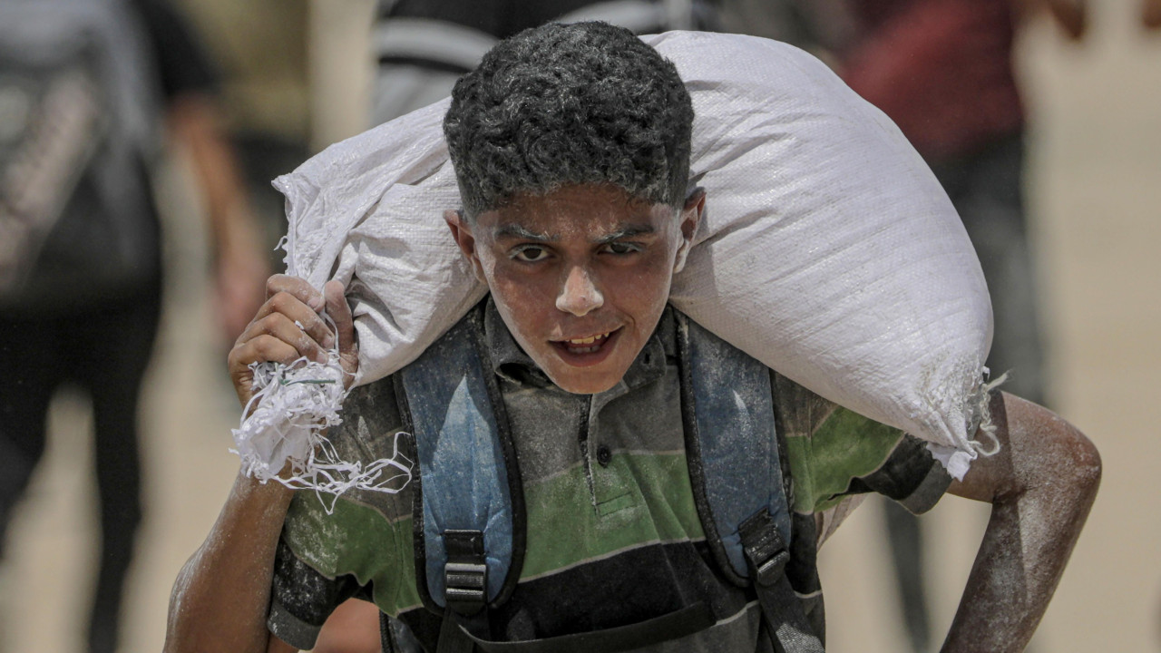 Palestinski dečak nosi kesu brašna blizu punkta za podelu hrane u Zikimu, na severu Gaze, 8. avgusta 2025. godine.