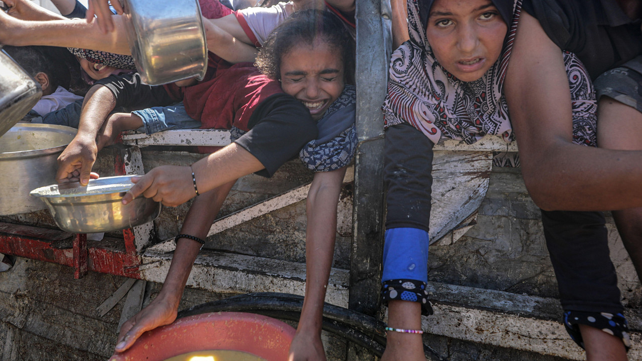 Interno raseljeni Palestinci i mala deca, drže lonce dok dobijaju hranu iz dobrotvorne kuhinje u gradu Gazi 4. avgusta 2025.