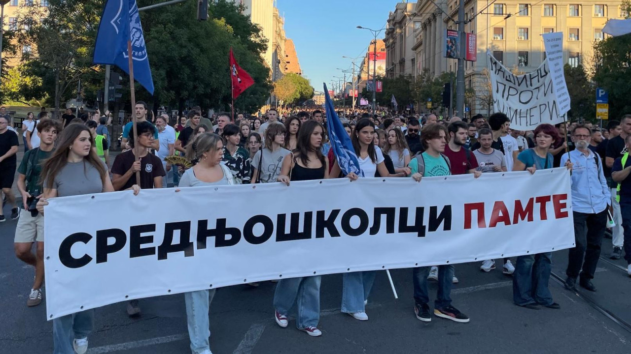 Ljudi drže u ruci transparent i šetaju
