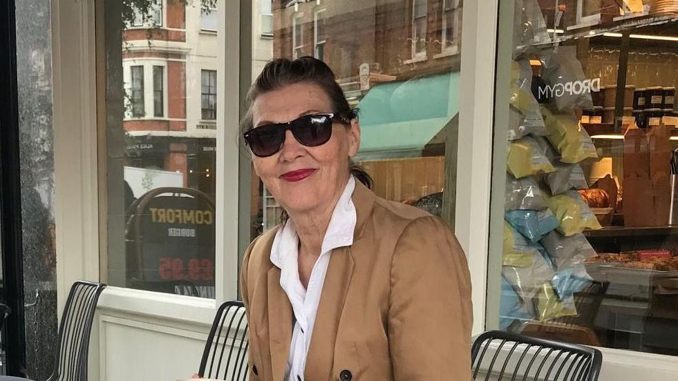 Žena sa sunčanim naočarama sedi na stolici 