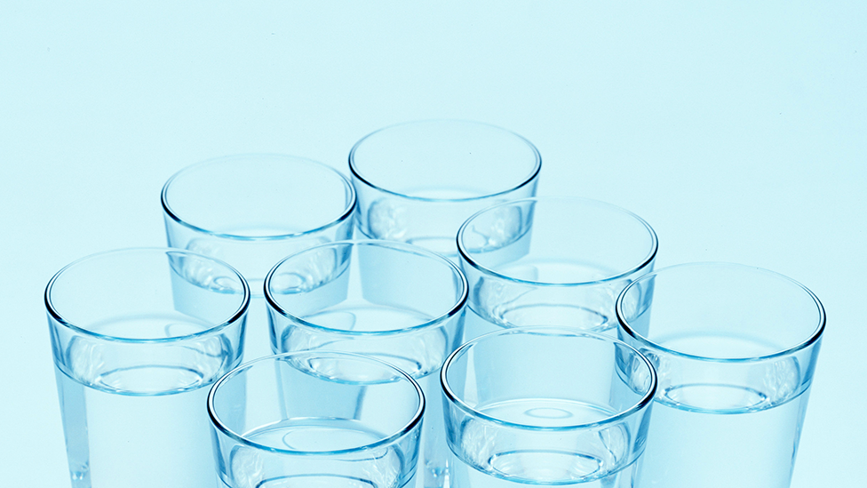Osam providnih čaša napunjenih vodom. Svaka čaša je ravnomerno razmaknuta.