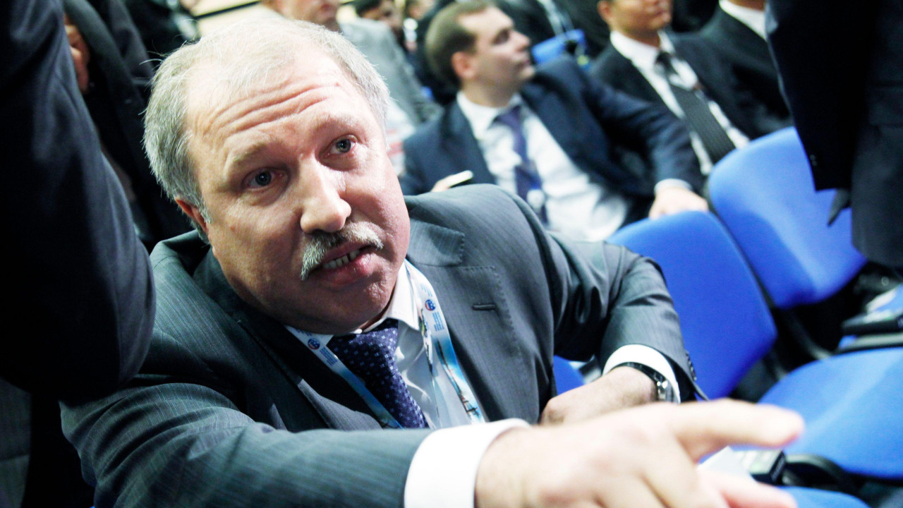 Eduard Hudainatov, predsednik naftne kompanije Rosnjeft, prisustvuje Međunarodnom ekonomskom forumu u Sankt Peterburgu (SPIEF) 17. juna 2011. godine. Pokazuje na nešto iza kamere dok sedi na plavim konferencijskim stolicama. Delimično je ćelav, ima sedu kosu i sede brkove i nosi sivo odelo. Ostali delegati sede iza njega.