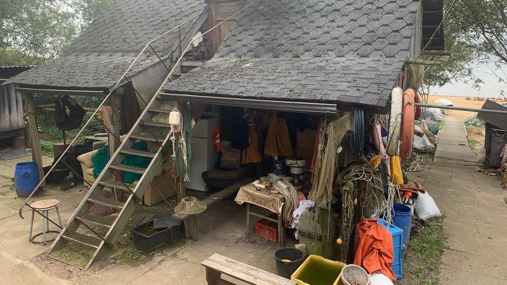 Drvena kuća ispred koje su ribarka odela, užad, mreže