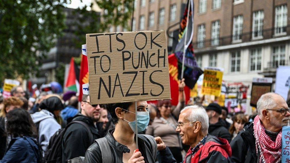 u redu je udariti nacistu, žena nosi transparent sa porukom: U redu je udariti nacistu