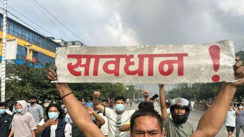 muškarac drži transparent sa ispisanim crvenim slovima