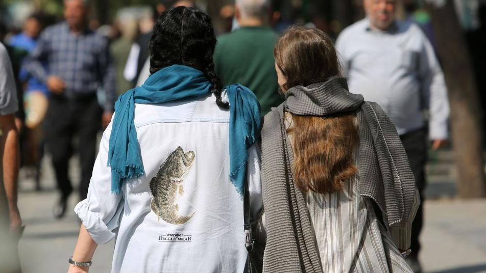 Dve devojke šetaju ogrnute maramom ali im se vidi kosa
