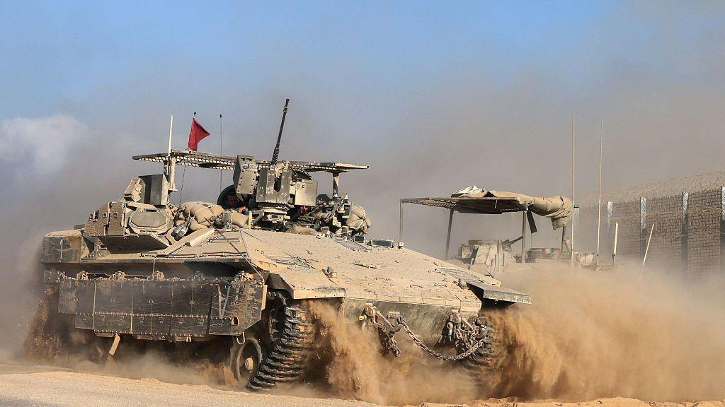 Izraelsko vojno vozilo prolazi pored granične ograde usred oblaka peska i prašine