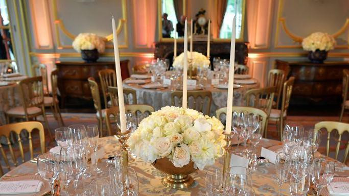 postavljeni stolovi sa luksuznim escajgom i belim ružama u sredini 